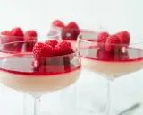 Flera glas med krämig pannacotta, toppad med hallon och en röd sås. En perfekt dessert i glas.