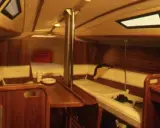 Intérieur chaleureux d'un voilier, avec banquettes en cuir crème, boiseries sombres et hublots. Le **selection 37 interieur** offre un espace confortable pour la vie à bord.