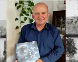 Uśmiechnięty mężczyzna trzyma książkę "Świat". Czyżby to był gajowy, który opowiada o leśnych tajemnicach?