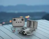 DJI Mini 2 z pilotem, bateriami i modułem do śledzenia obiektu, gotowy do lotu nad nocnym miastem.