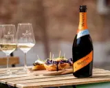 Mionetto alkoholfreier Aperol 0.0% mit zwei Gläsern und leckeren Bruschettas auf einem Holztisch.