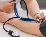 Lekarz mierzy ciśnienie pacjentowi. Wynik wskazuje ciśnienie rozkurczowe powyżej 100, co wymaga dalszej diagnostyki.