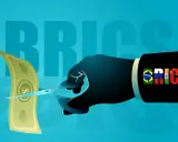 Ręka w garniturze z flagami BRICS przecina dolara, symbolizując nową walutę BRICS.
