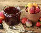Ein Glas selbstgemachte Marmelade mit frischen Früchten daneben. Die Frage "wie lange ist selbstgemachte Marmelade haltbar" beschäftigt viele Hobbyköche.