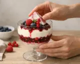 Verrine de dessert aux fruits rouges et crème, garnie d'une feuille de menthe.