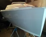 Le bateau Neptune 550, prêt pour sa nouvelle peinture, repose sur des supports dans un atelier.