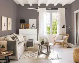 Salones pequeños con encanto: un sofá beige, sillón de mimbre, mesas de madera y detalles decorativos crean un espacio acogedor.
