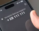 Vorsicht: Betrug möglich! Ein Finger tippt auf dem Smartphone, um Spam-Anrufe zu blockieren.