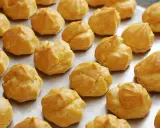 Une fournée de choux à la crème dorés, prêts pour la cuisson. Ils attendent patiemment d'être transformés en délices.