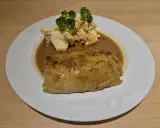 Ein herzhaftes Krautwickel Rezept auf einem Teller mit Kartoffelbrei und Sauce, garniert mit Petersilie.