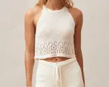 Top a ganchillo blanco con detalles calados en el bajo.