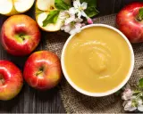 Frische Äpfel und eine Schüssel mit selbstgemachtem Apfelmus, garniert mit Apfelblüten. Ein Genuss für alle Sinne!