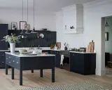 Elegancka kuchnia z ciemnogranatowymi, **czarnymi meblami kuchennymi**. Centralna wyspa i zabudowa tworzą spójną całość.