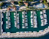 Widok z lotu ptaka na port w Chorwacji, pełen białych jachtów i łodzi zacumowanych w turkusowej wodzie.