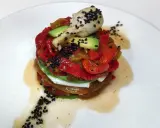 Torre de pimientos del piquillo asados, aguacate y queso fresco, coronada con un alcachofa y semillas de sésamo negro.