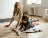 Mama i dziecko ćwiczą jogę. To świetne gry i zabawy ruchowe przykłady dla całej rodziny.