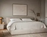 Une chambre beige apaisante avec un lit bas, une table de chevet sculpturale et une œuvre d'art abstraite.