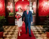 Para idzie po czerwonym dywanie, ona w białej sukni z bukietem, on w granatowym garniturze. To ich ślub rzymski.