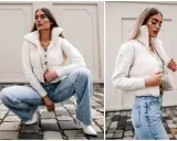 Elegancka stylizacja: jak nosić kamizelkę puchową z jeansami i swetrem. Kremowa kamizelka puchowa, biały sweter z warkoczami, szerokie jeansy i białe botki.