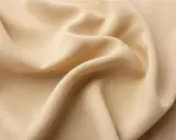 A close-up of draped beige viscose fabric. It feels smooth and cool, like silk, with a subtle sheen.