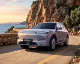 Un Geely plateado recorre una carretera costera en España al atardecer, con el mar Mediterráneo y acantilados rocosos de fondo.