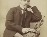 Portret eleganckiego mężczyzny z wąsami, w garniturze i z książką. Może to być znany poeta.