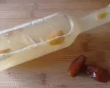 Flasche mit Flüssigkeit und Fruchtstücken, bereit zum Hefe selber machen. Daneben liegen zwei Datteln.