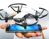 Kleine Drohne schwebt über einem Smartphone, das die tello app anzeigt.