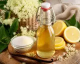 Bouteille de sirop de sureau, citrons, sucre et fleurs de sureau. Une recette de grand-mère pour un sirop fait maison.