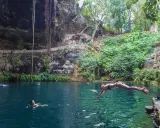 Una ragazza si tuffa nel **cenote Zaci**, un'oasi naturale con acque cristalline e vegetazione lussureggiante.