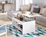Mesa elevable pequeña blanca con compartimentos, junto a un sofá gris y una silla azul, sobre una alfombra geométrica.