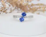 Elegancki pierścionek z dwoma szafirami i białymi kamieniami. Szafir, jak mata, otoczony blaskiem.