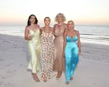 Cuatro mujeres elegantes en la playa al atardecer, celebrando una preboda.