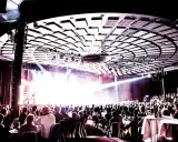 Publik njuter av en konsert på Rondo Liseberg. Scenen badar i ljus, taket är dekorerat med akustikpaneler.