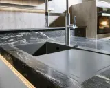 Moderne Küche mit Spüle und Armatur auf einer dunklen Keramik-Arbeitsplatte. Vorsicht vor Bruchgefahr bei unsachgemäßer Handhabung.