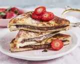 Gestapelte French Toast mit Nutella, bestäubt mit Puderzucker und garniert mit Erdbeeren. Ein süßer Genuss!