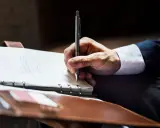 Mężczyzna w garniturze pisze w notatniku. Może to być wzór wniosku o umorzenie długu u komornika.