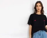 Kobieta w czarnym t-shircie z haftowanymi kwiatkami i jeansach. Stylowy sposób, jak nosić t-shirt w spodniach.