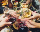 Ręce wznoszą kieliszki z winem, białe i czerwone, do toastu. Rozpoczyna się radosne świętowanie i trawienie alkoholu.