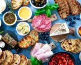 Eine köstliche italienische Vesperplatte mit Salami, Käse, Brot, Oliven und eingelegtem Gemüse.