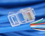 Gros plan sur un connecteur transparent de câble réseau RJ45, révélant les fils colorés prêts pour un débit de câble RJ45 optimal.