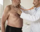 Lekarz osłuchuje klatkę piersiową starszego mężczyzny stetoskopem.