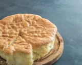 Un gâteau raté, un peu affaissé, sur une planche en bois. Sa texture est spongieuse et sa croûte dorée.