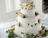 Elegancki tort weselny ozdobiony bukietem brzoskwiniowych i białych róż, margaretek i zieleni. Piękne, jakie żywe kwiaty na tort!