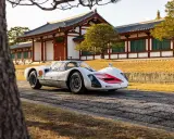 Ein weißer Porsche 966 mit roten Akzenten steht vor einem traditionellen japanischen Gebäude.