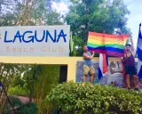 Two men proudly hold a rainbow flag at Laguna Beach Club, celebrating gay pride in Guatemala.