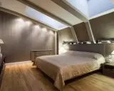Chambre douillette avec un lit confortable sous une **tête de lit sous pente** et un puits de lumière illuminant la pièce.