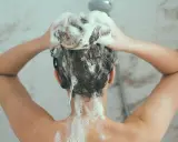 Person wäscht sich die Haare mit schaumbildendem Shampoo. Die Stiftung Warentest hat Olaplex-Produkte untersucht.