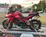 Czerwony Ducati na przyczepie, zabezpieczony pasami do transportu. Gotowy do drogi.