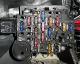 Caja de fusibles de coche con varios fusibles de colores y etiquetas. Aprende cómo quitar un fusible del coche para reparaciones.